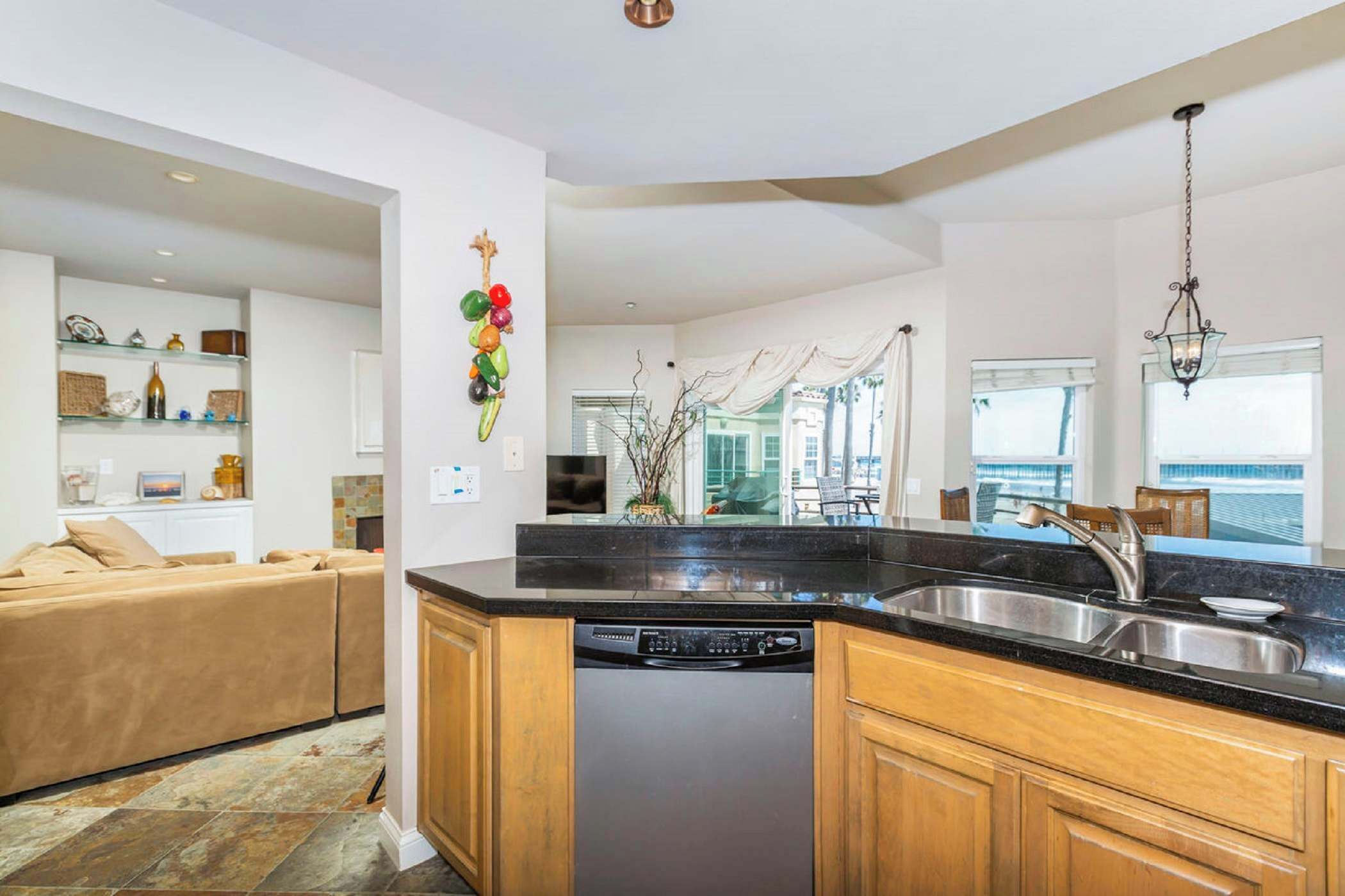 A modern kitchen with a dishwasher, wooden cabinets, and a black countertop.