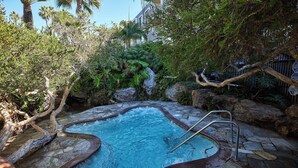 A hot tub surrounded by natural rock formations and lush greenery. - North Coast Village D204 (Oceanside)