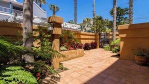 A gated entrance with a tiled pathway leading to a building, surrounded by palm trees and various plants. - Oceanview Townhome Pvt.deck M-C (Oceanside)