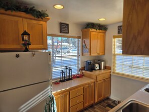A compact kitchen with wooden cabinets, a refrigerator, a coffee maker, and a toaster.