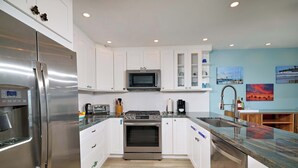 Una cocina moderna con armarios blancos, electrodomésticos de acero inoxidable y encimera de granito.