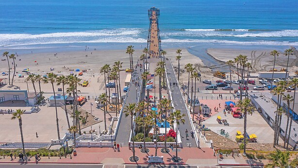 A pier extending into the ocean with a beach and palm trees in the foreground. - Sunrise & Sunset by the Sea  812-1 (Oceanside)