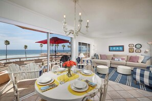 A dining area with a view of the ocean, a chandelier, and a sofa with cushions. - 501P-7 Panoramic Ocean Views! (Myrtle Beach)