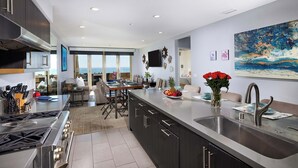 Een moderne keuken met een groot schiereiland, roestvrijstalen apparatuur en uitzicht naar buiten.