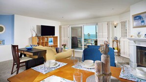 Ein Wohnzimmer mit Essbereich, einem Fernseher und Meerblick.