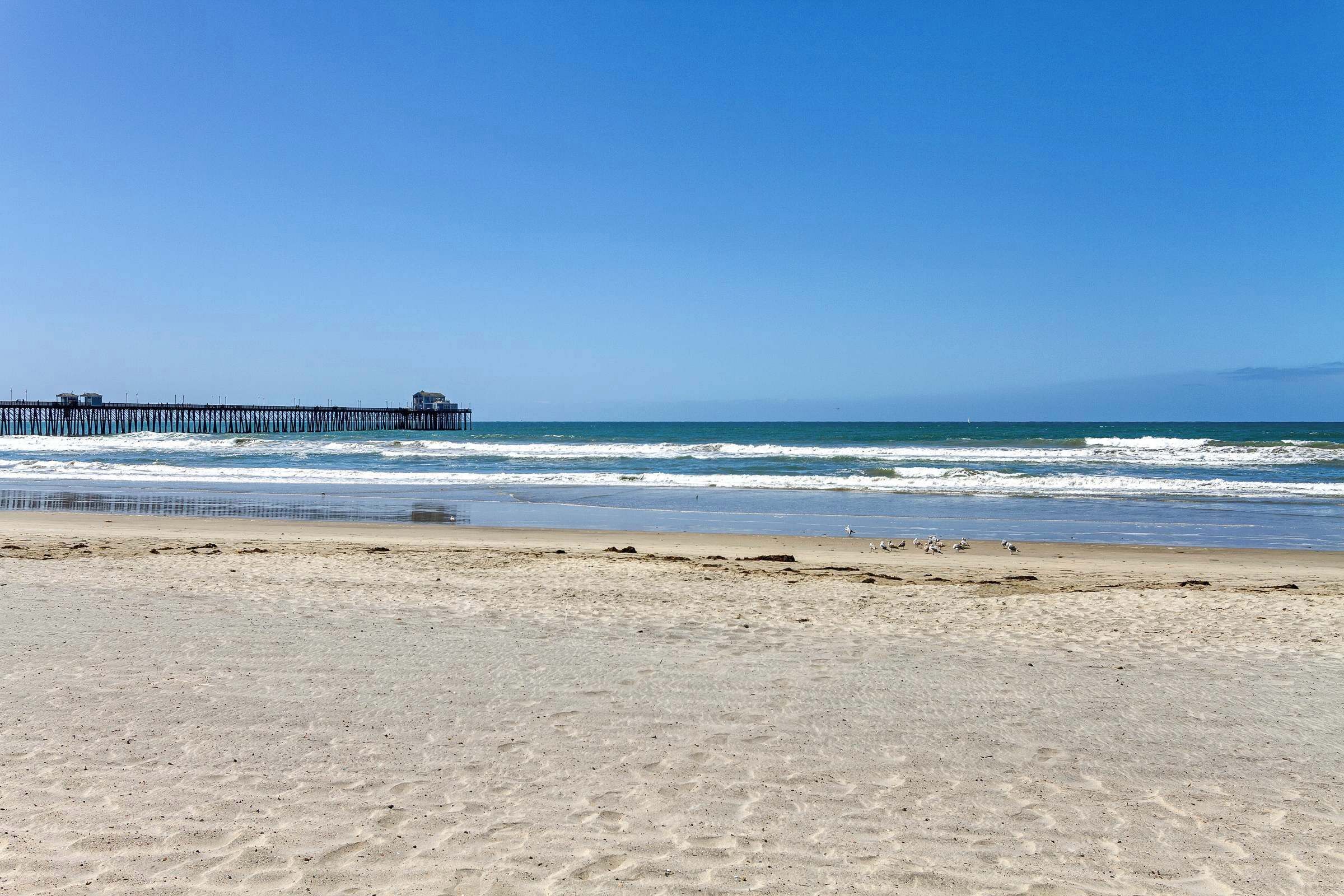 A beach with a pier extending into the ocean.