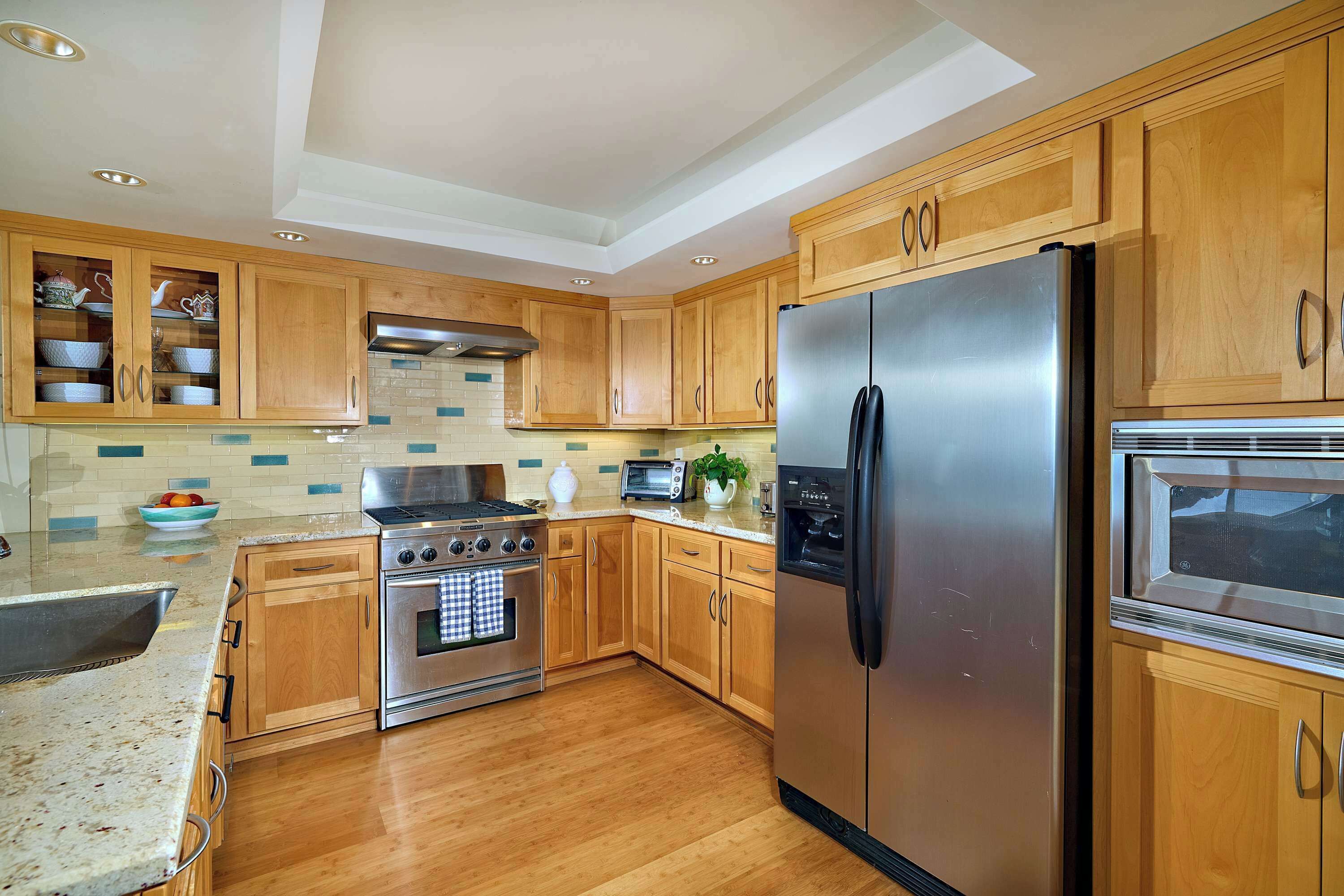 Una cocina moderna con armarios de madera, electrodomésticos de acero inoxidable y un salpicadero de azulejos.