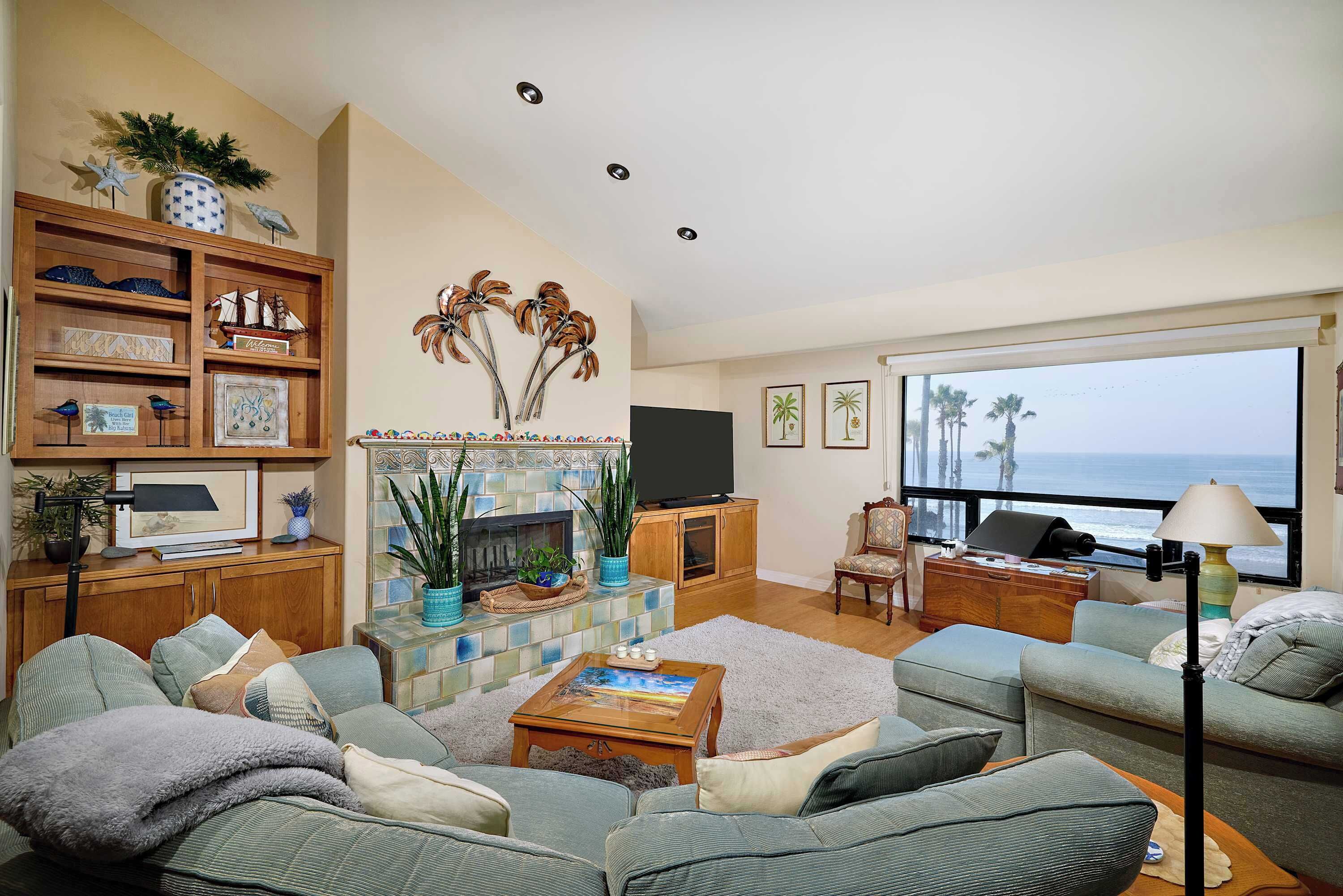 A living room with a fireplace, a large window with a view of the ocean, and a television.