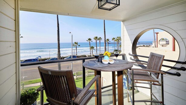 A balcony with a table, two chairs, and a view of the ocean. - 152-4 Coastal Luxury with Panoramic Ocean View (Oceanside)