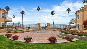 A courtyard with a tiled floor, palm trees, and flower beds. - 5N-31 Beach View, BBQ & Jacuzzi! (Oceanside)