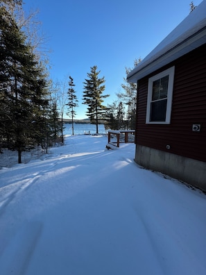 Eine Holzhütte mit verschneitem Deck und Seeblick.