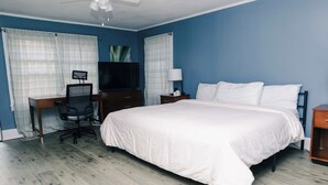 Une chambre à coucher avec un grand lit, un bureau avec une chaise, une télévision et une table de chevet avec une lampe.