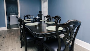 Une salle à manger avec une table en bois foncé, dressée pour six personnes, entourée de six chaises.