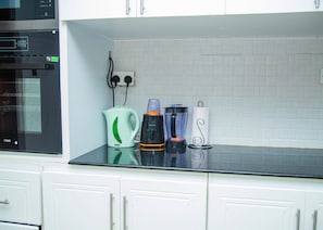 A kitchen with a microwave, a kettle, a blender, and a paper towel holder on the counter.