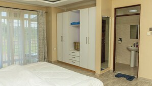 A bedroom with a large bed, wardrobe, and a bathroom with a sink and mirror.