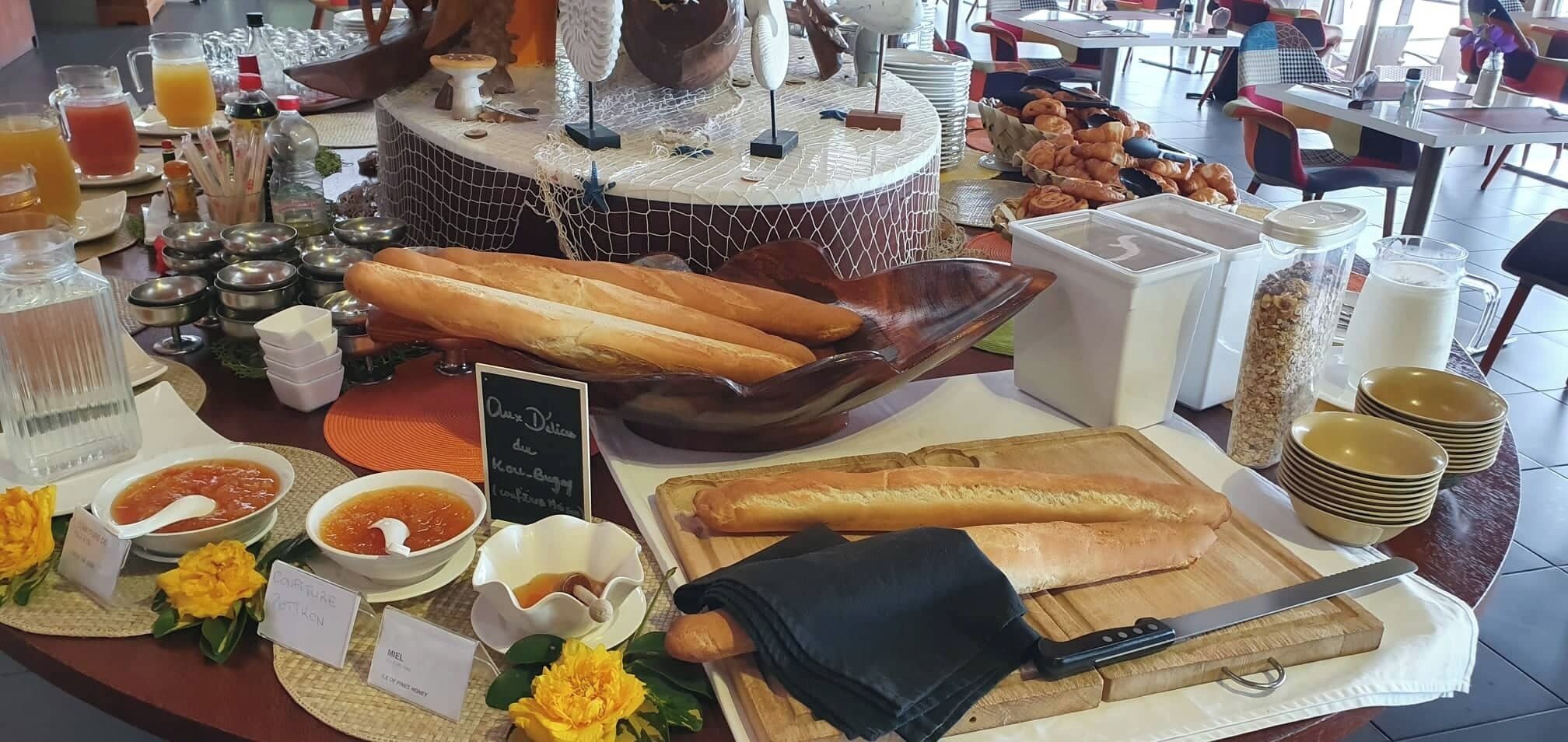 A breakfast buffet with various food items, including bread, pastries, and condiments.