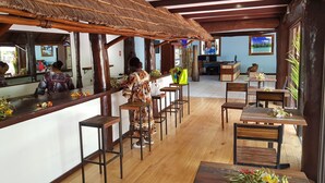 A restaurant with wooden floors, a thatched roof, and a bar area. - Hôtel KOU-BUGNY (L'Ile-des-Pins)