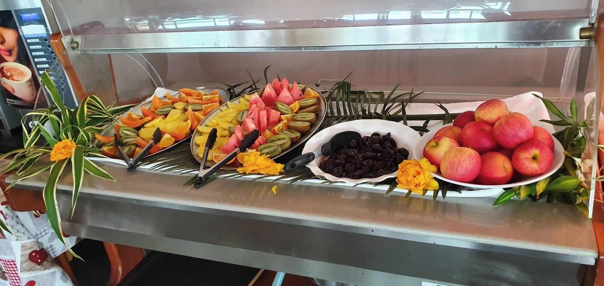 A buffet with various fruits and a bowl of raisins.