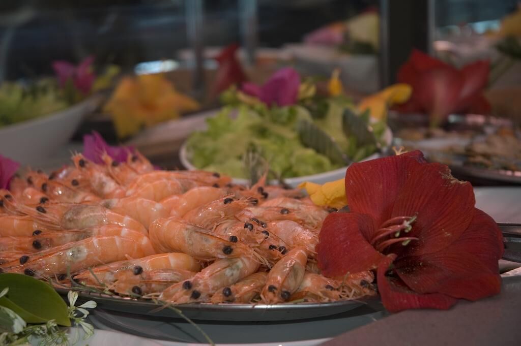 A seafood platter with shrimp and a red flower.