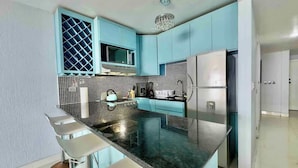 A modern kitchen with a central island, stainless steel appliances, and blue cabinetry. - Oceanfront Rosarito Balcony, Beach & Amazing Sunsets (Playas de Rosarito)