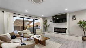 A modern living room with a sofa, chairs, a coffee table, a fireplace, and a TV. - Wellness Bnb - Your San Diego Retreat! (San Diego)