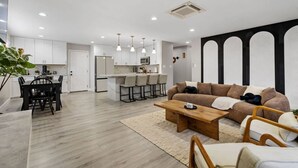 A modern living room with a sofa, coffee table, and dining area. - Wellness Bnb - Your San Diego Retreat! (San Diego)