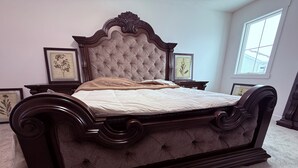 A large, dark wood four-poster bed with a tufted headboard and a beige bedspread. - YEG keswick townhouse retreat (edmonton)