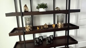 A dark wooden multi-tiered shelf unit with decorative items and a potted plant. - YEG keswick townhouse retreat (edmonton)