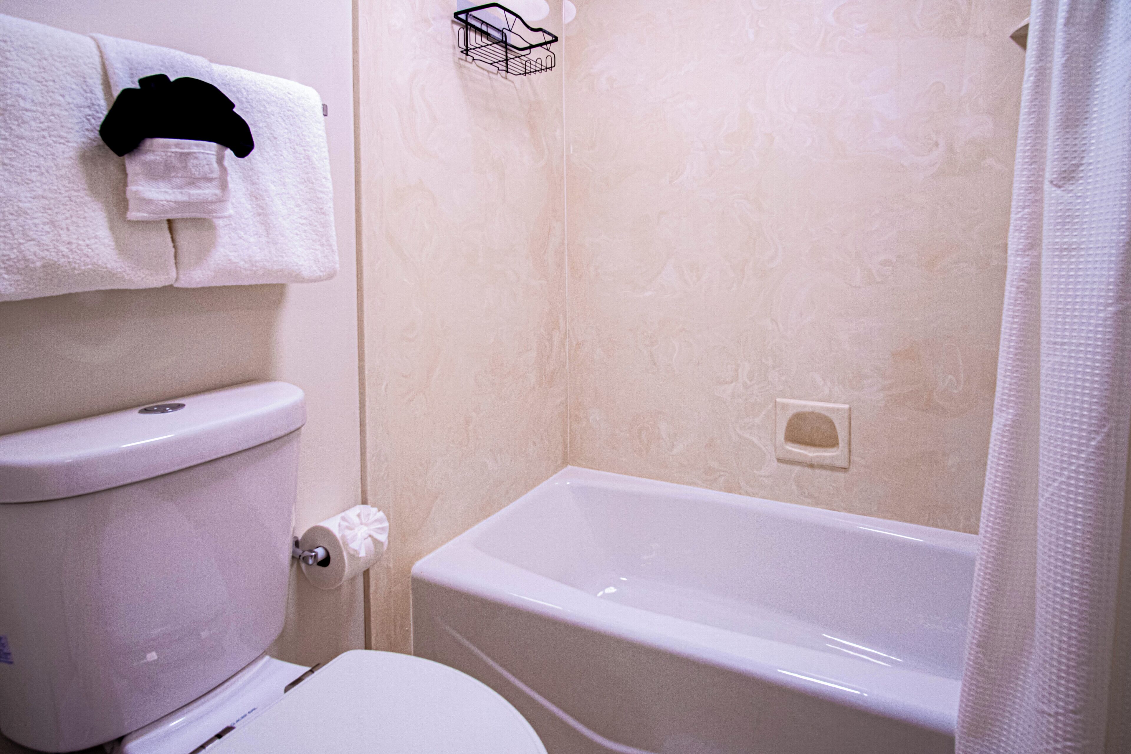 Un baño con inodoro, bañera y perchero para toallas.
