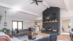 Un salón espacioso con chimenea, sofás de cuero y una cocina moderna al fondo.