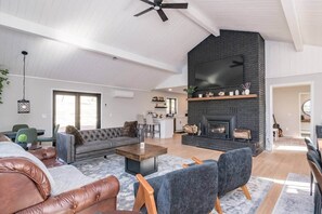 Ein geräumiges Wohnzimmer mit Kamin, Ledersofas und einer modernen Küche im Hintergrund.