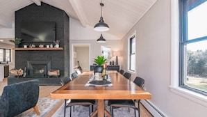 Un comedor espacioso con una larga mesa de madera, sillas negras y una lámpara colgante.