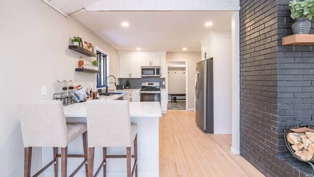 Una cocina moderna con armarios blancos, electrodomésticos de acero inoxidable y una zona de comedor de madera.