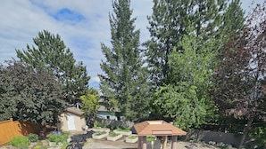 Patio con piscina, terraza de madera y un pequeño pabellón.