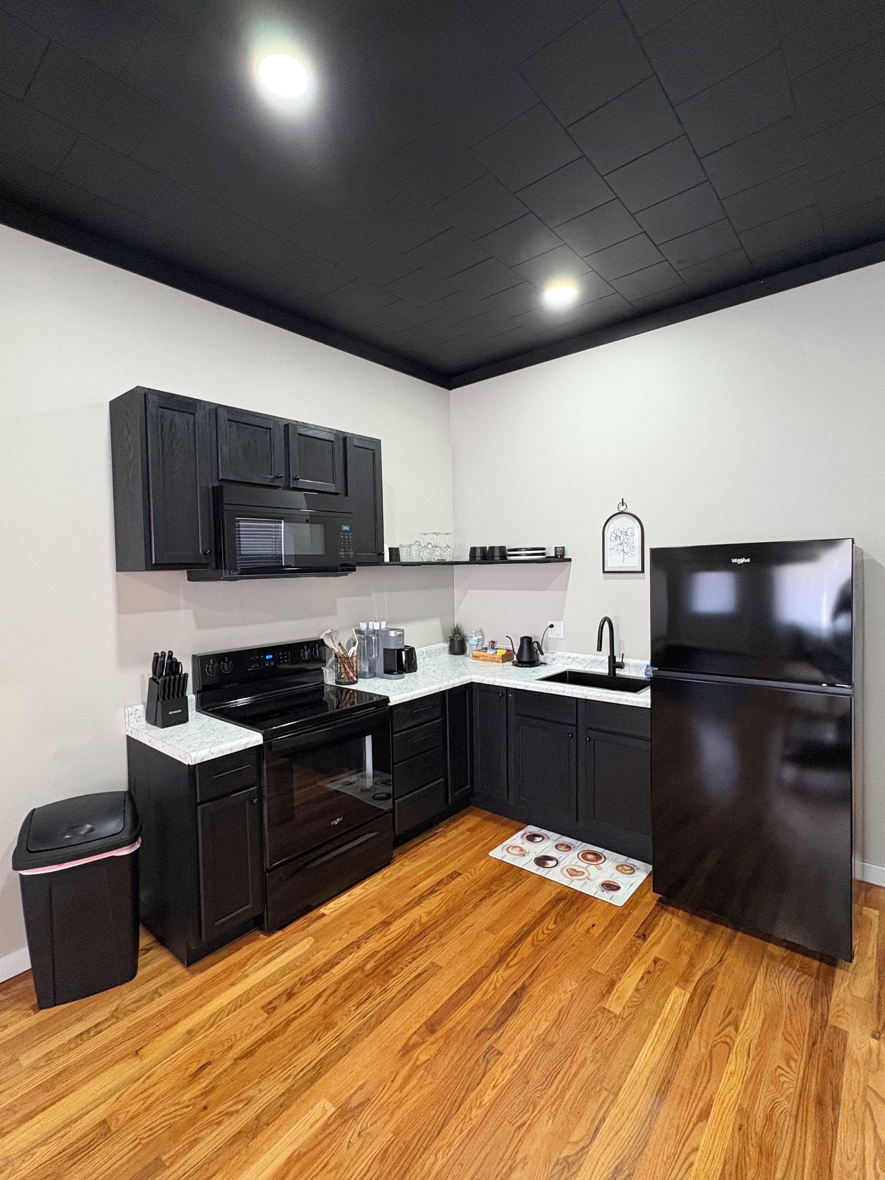 Una cocina moderna con armarios negros, un refrigerador de acero inoxidable y un microondas.