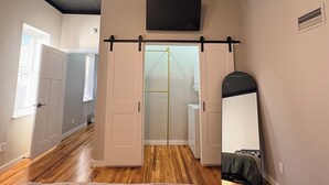 A room with a sliding door, a mirror, and a ceiling-mounted TV.