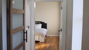 A bedroom with a bed, wooden flooring, and a sliding door.