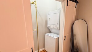 A laundry room with a washing machine and dryer, wooden flooring, and a mirror.