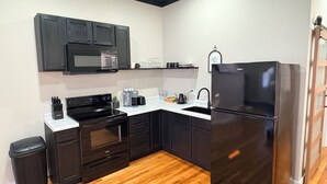 A modern kitchen with dark cabinetry, a stainless steel refrigerator, a microwave, and a built-in oven.