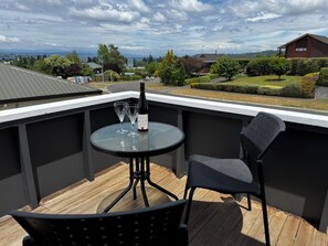Ein Balkon mit einem runden Tisch, zwei Weingläsern und einer Weinflasche.