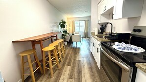 Una cocina con taburetes de madera, estufa y lavamanos.