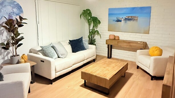 Een moderne woonkamer met een witte bank, een houten salontafel en een plafondventilator.