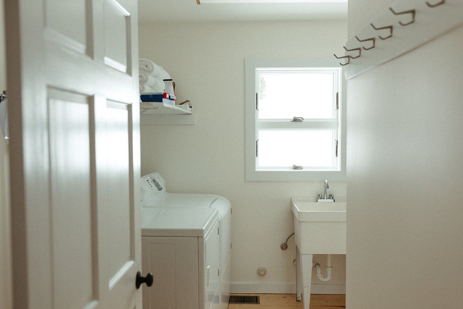 Una habitación pequeña con paredes blancas, una ventana, una lavadora y un lavabo.