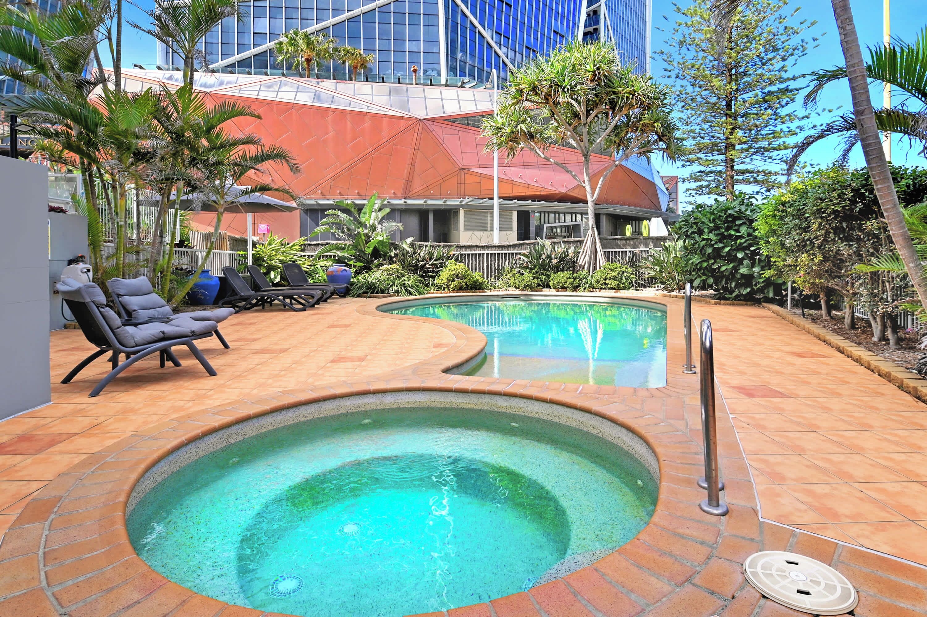 A pool area with lounge chairs and a hot tub.