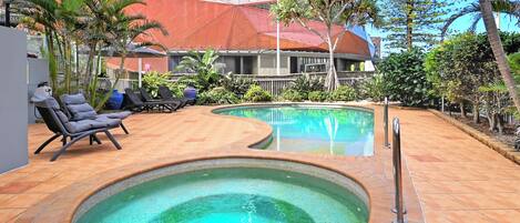 Un área de piscina con sillones reclinables y un jacuzzi.