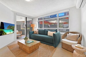 Ein modernes Wohnzimmer mit einer Couch, einem Couchtisch und einem Korbstuhl.