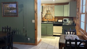A cozy cabin interior with a dining area, kitchen, and a framed picture on the wall. - Allen Falls Private Woodland Cabin on 30 acres (Potsdam)