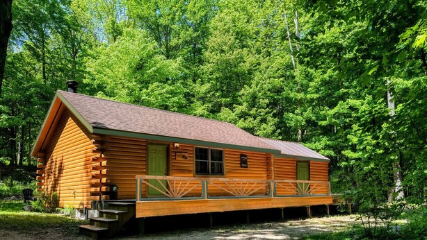 A wooden cabin with a porch, surrounded by dense forest. - Allen Falls Private Woodland Cabin on 30 acres (Potsdam)