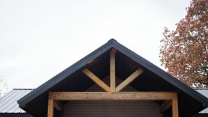 A house with a gray exterior, a black front door, and a wooden porch with steps. - One Eyed Odie's Cozy 3-bed, 1-bath home with a relaxing hot tub. (Cove)