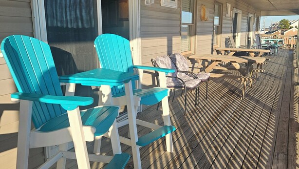 Eine überdachte Terrasse mit Sitzgelegenheiten im Freien, darunter Stühle und Tische, und Blick auf die Umgebung.